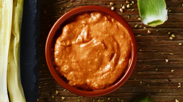 Top view of romesco sauce in a clay bowl on a wooden table