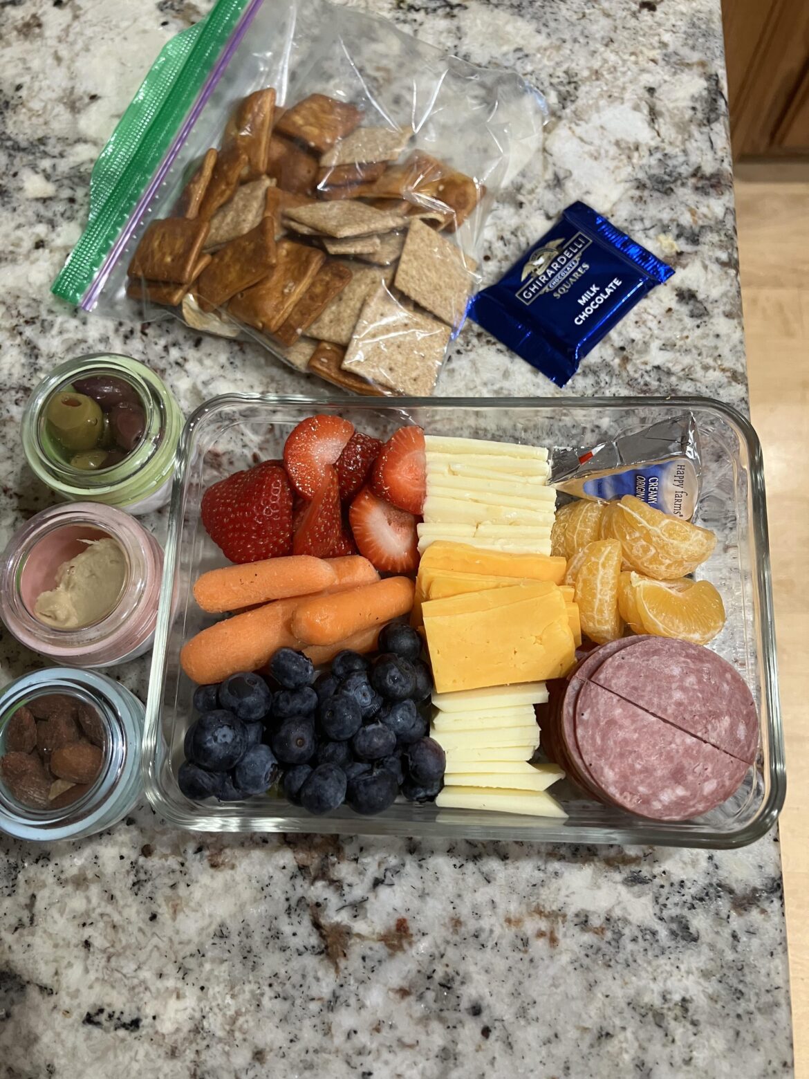 Packing my wife’s lunch for tomorrow - aged white cheddar, sharp provolone, fresh squeaky Colby, laughing cow (Aldi version), almonds, hummus, olives, summer sausage, fruit, pretzel crackers and wheat thins. And some chocolate.