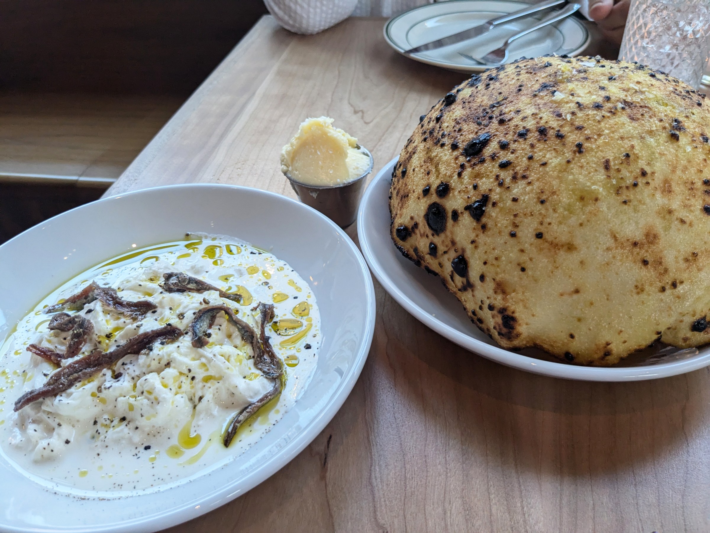 A puffy bread with lake of cream and cheese on the side.