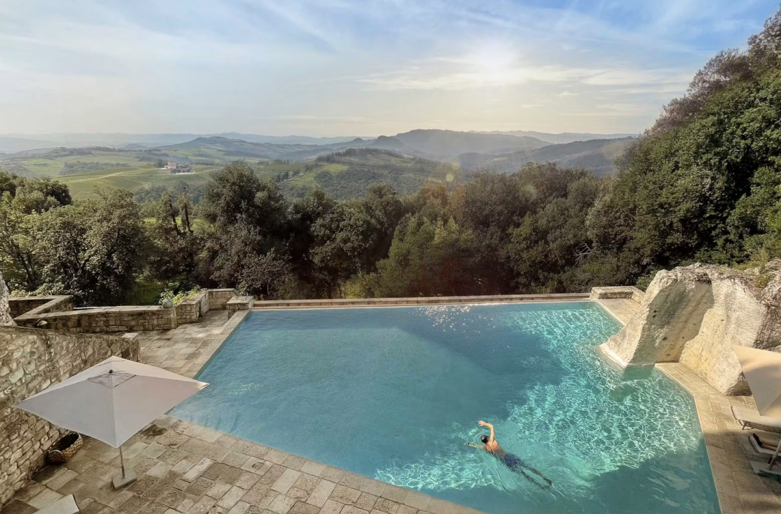 Image of saltwater infinity pool at the Tuscan villa Borgo Pignano, a green luxury hotel with views of the Tuscan woods.
