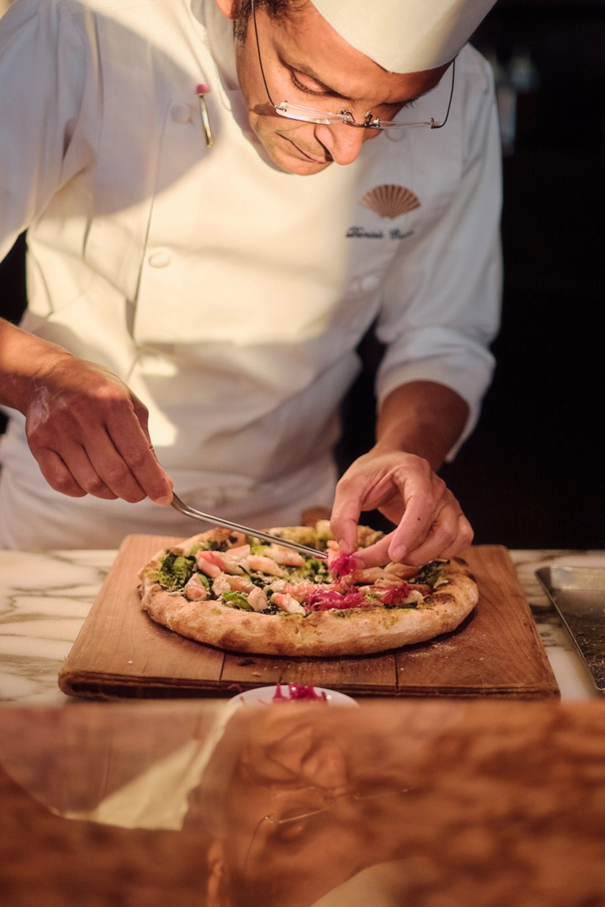A chef puts the finishing touches to a pizza