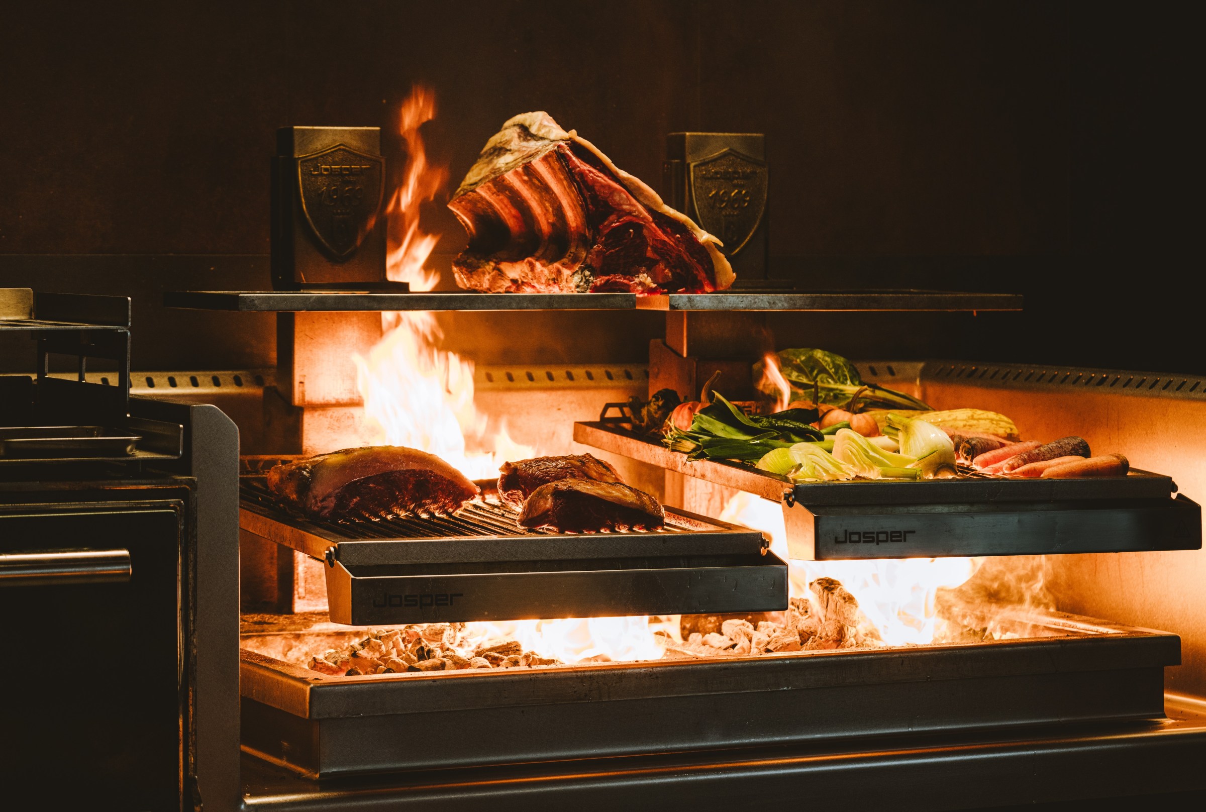 A double grill where meat and vegetables cook over a blazing fire.