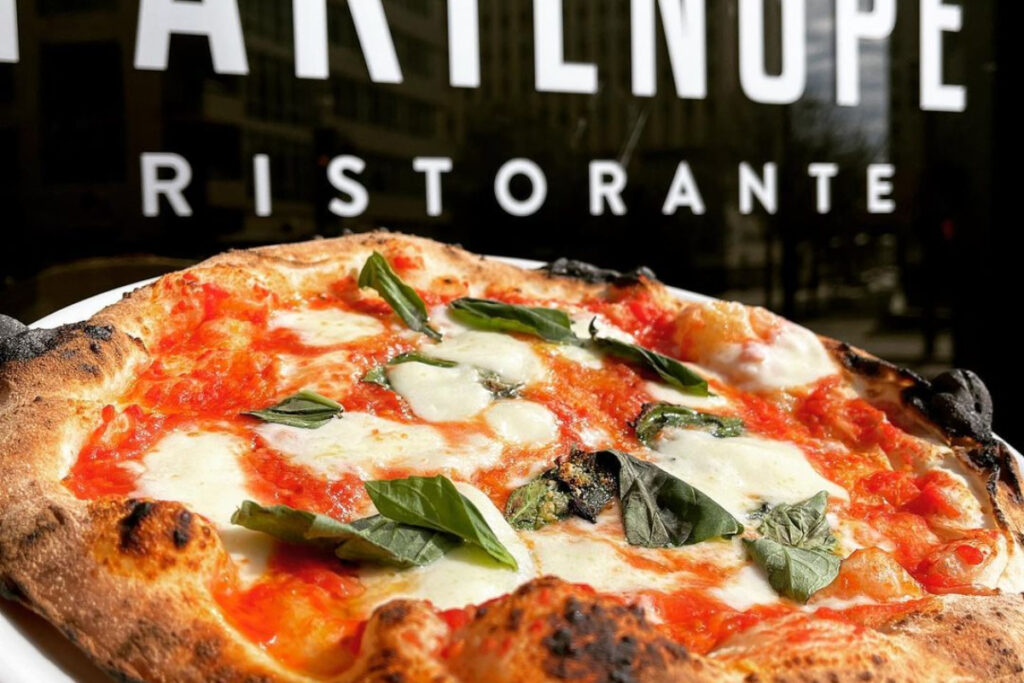 Image shows a traditional Neapolitan pizza in front of Partenope Ristorante in Dallas.