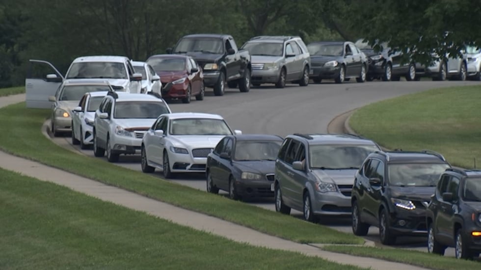 A row of cars stretched farther than the eye could see, leading up to the parking garage of...