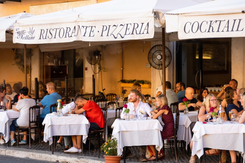 People dining at an outdoor restaurant in Piazza Navona, Rome.