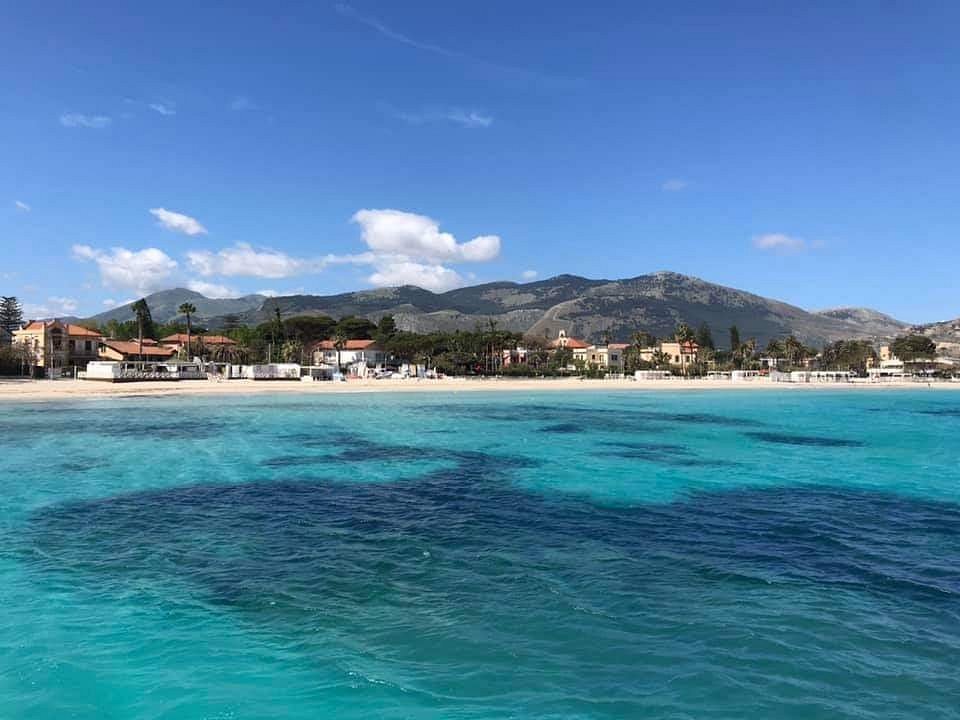 Mondello beach with turquoise water and mountains in the background.