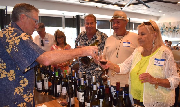 Kiwanian Ron Walker pours wine for Patti Barnhill while Kevin Dorris, center, and Robert Chantry wait their turns during the 2024 "Wine-Down Summer" event. (Elizabeth Marie Himchak)