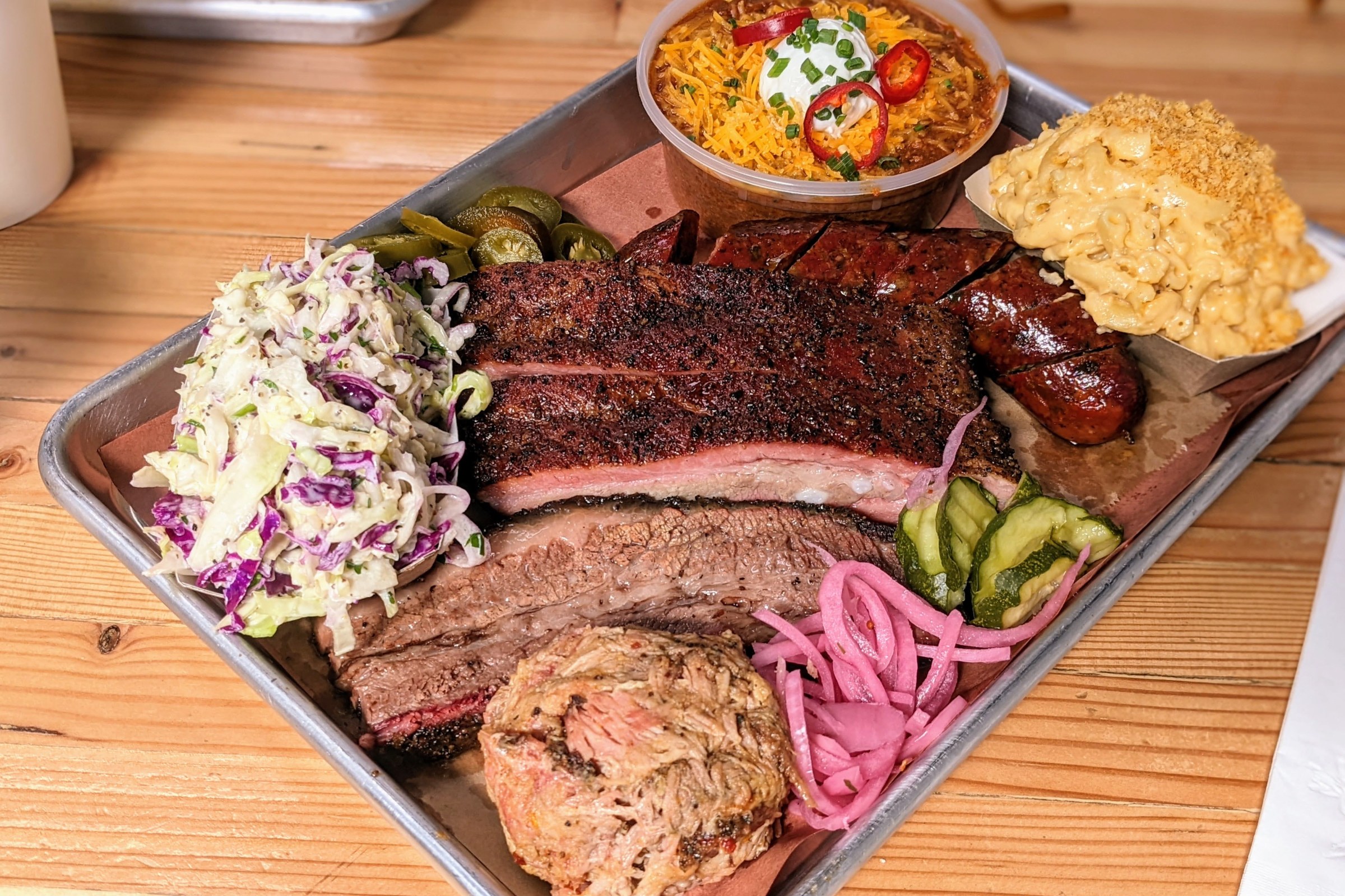 Smoked meats and sides on an aluminum tray.