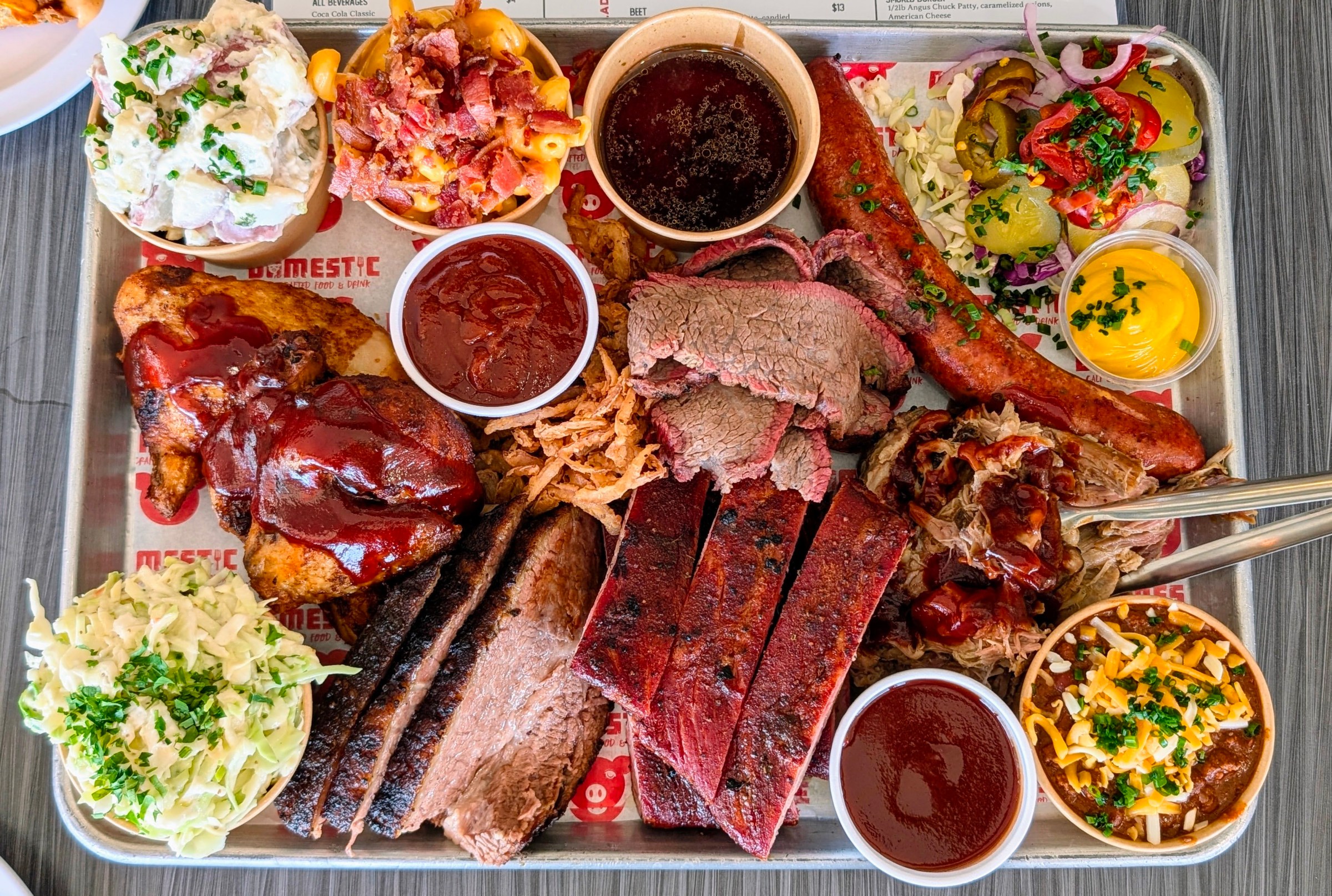 Smoked beef and ribs with colorful sides on an tray.
