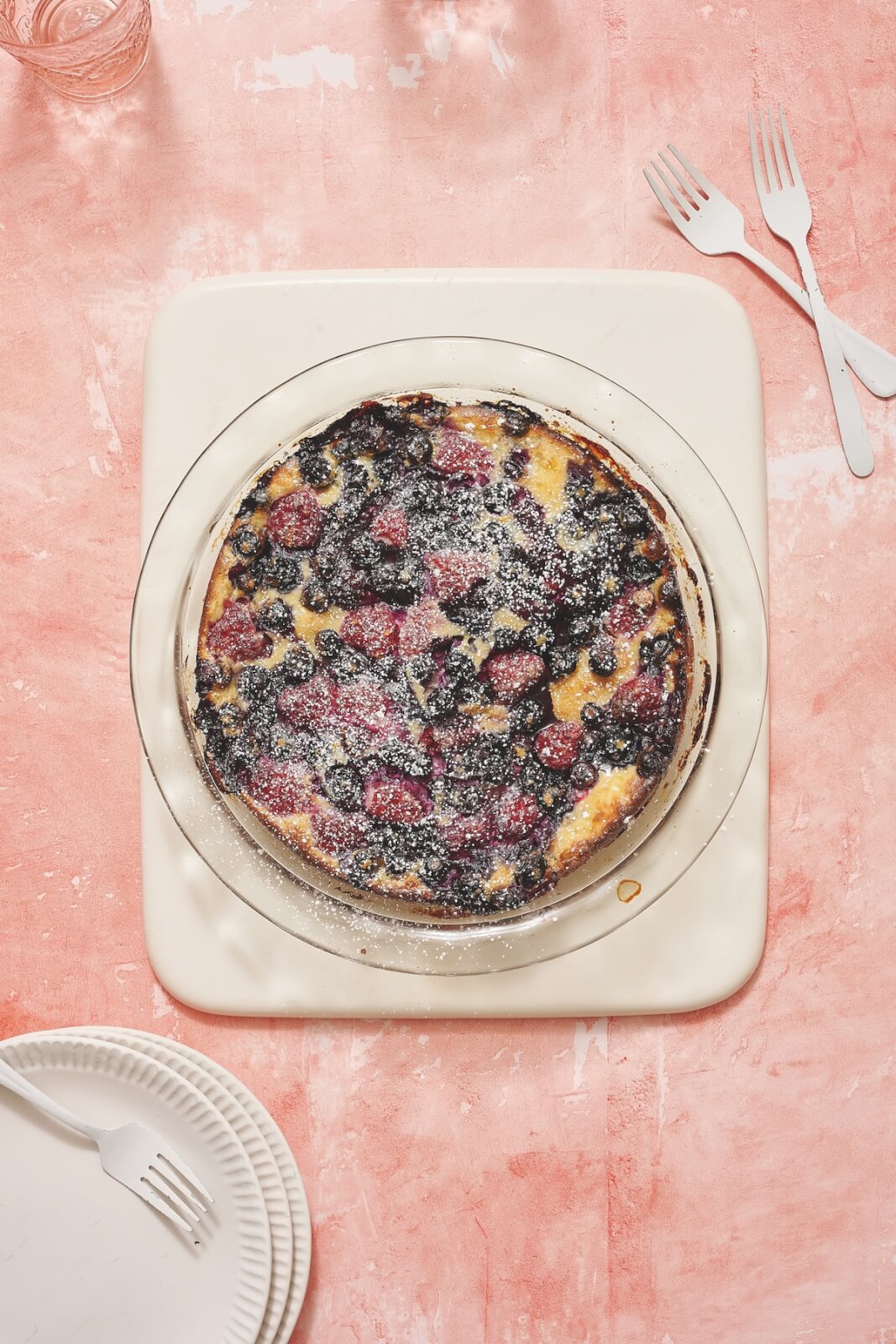 A blueberry clafoutis on pink counter.