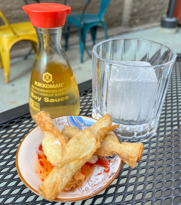 A soy sauce bottle filled with cocktail ingredients and a little dish of wontons