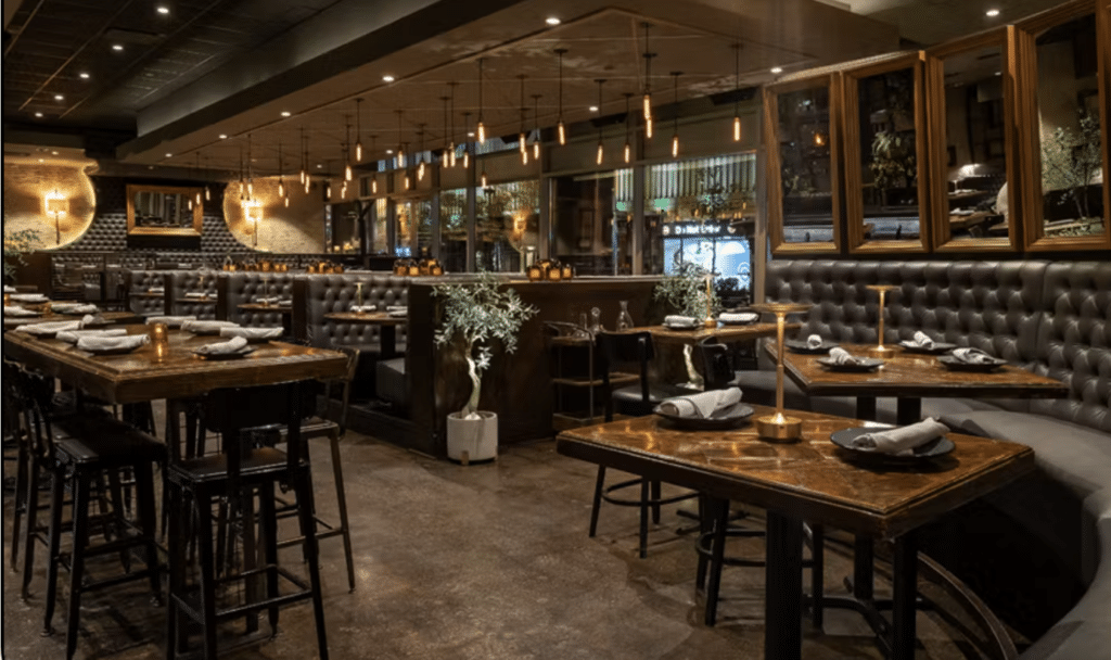 interior of dimly lit Siena tavern with wooden tables and chairs and plants around the restaurant