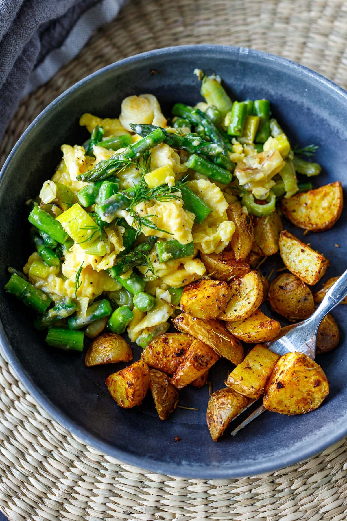 scrambled eggs with asparagus and leeks served with breakfast potatoes.