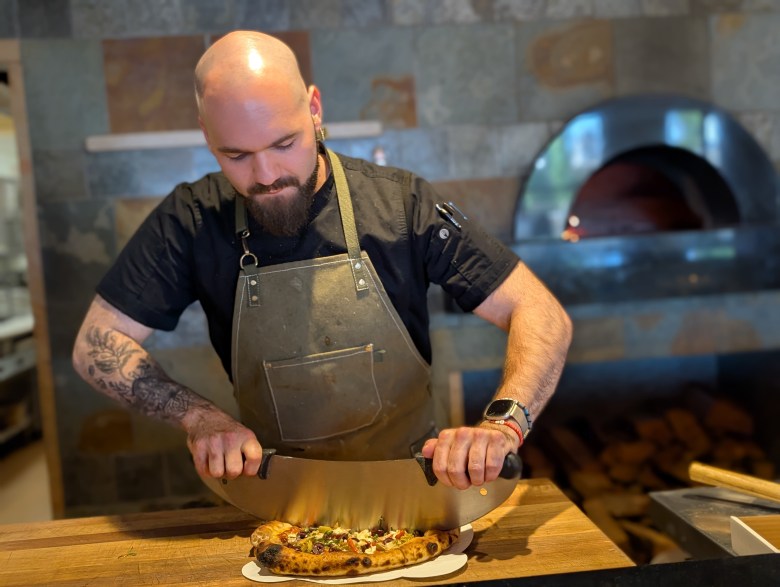 Zest head chef Chaney Shanley slicing pizza