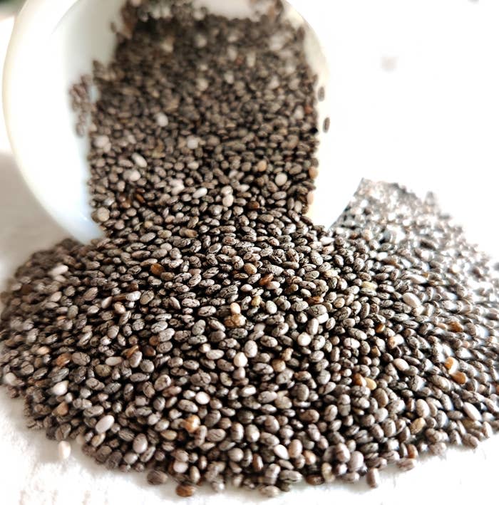 Chia seeds spilled from a container onto a surface, illustrating a healthy food option in an article categorized under Goodful