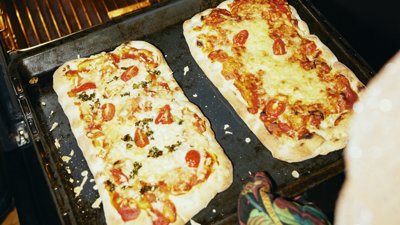 Person taking pizza out of oven
