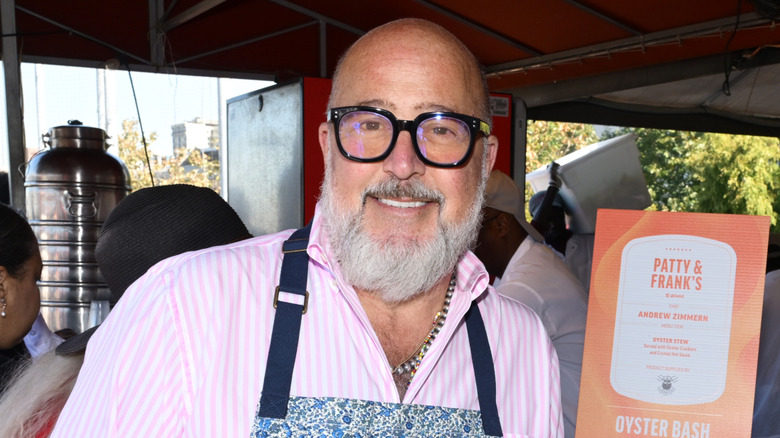 Andrew Zimmern wearing an apron and smiling