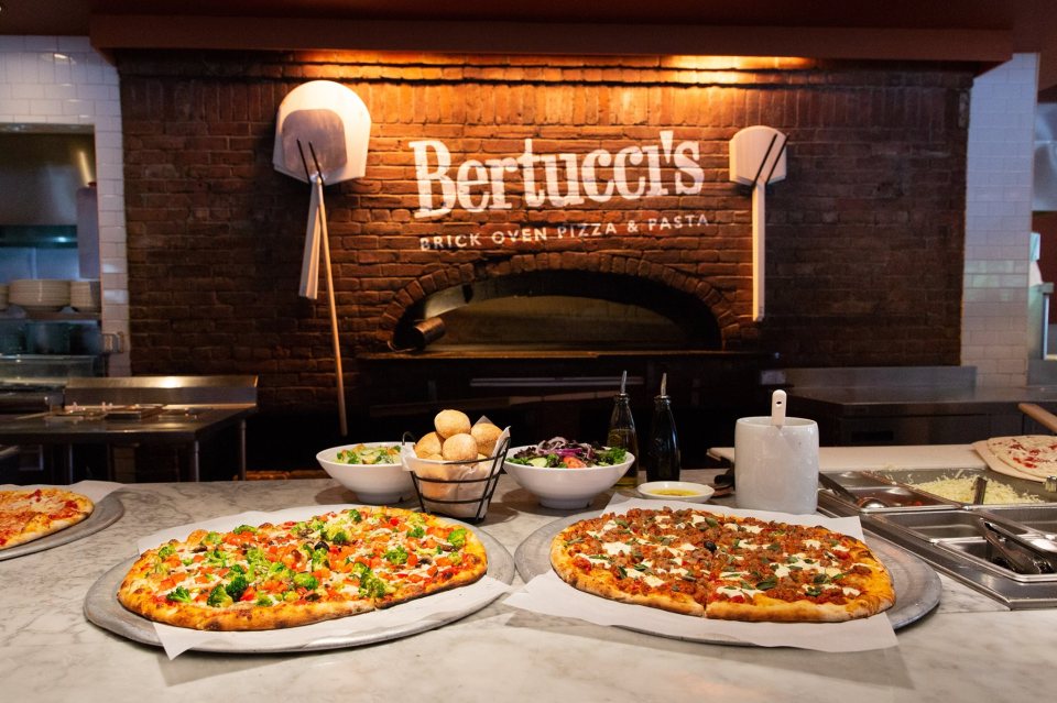 Two pizzas, salads, and bread at Bertucci's Italian Restaurant.