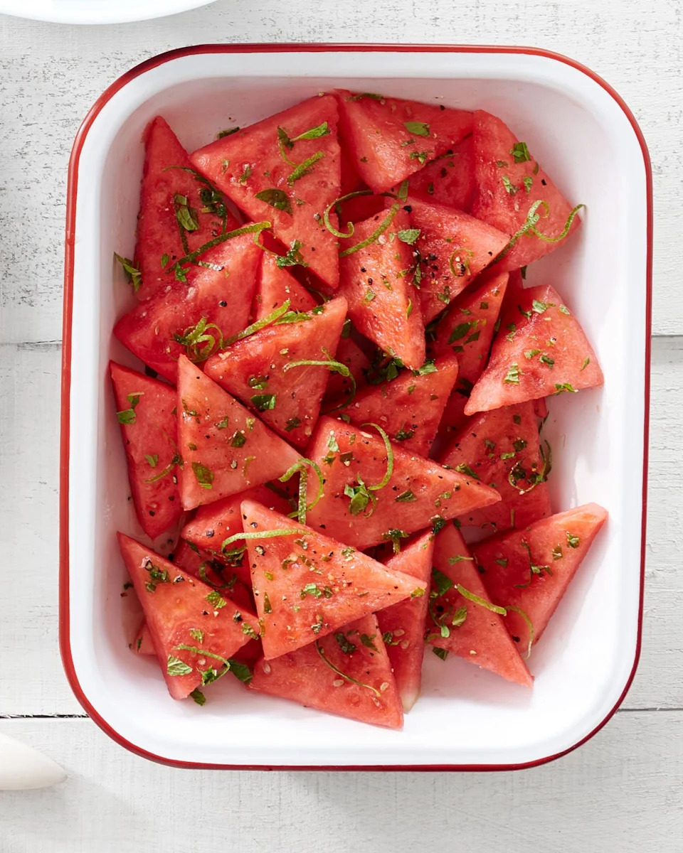 watermelon triangles with lime juice and mint on them in a white bowl