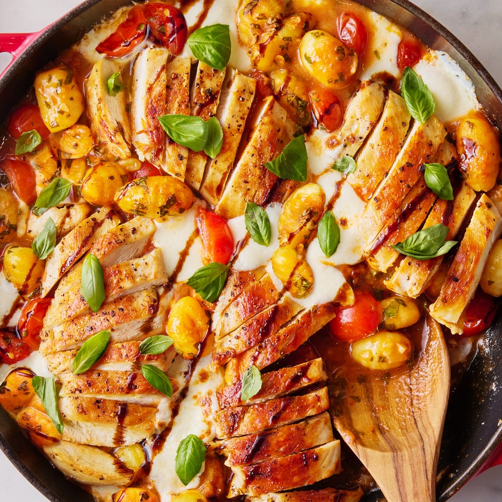chicken with gnocchi, tomatoes, and cheese in a red skillet