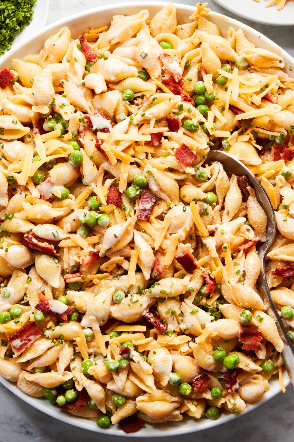 pasta noodles tossed with bacon, peas, and cheddar cheese all tossed in a creamy sauce