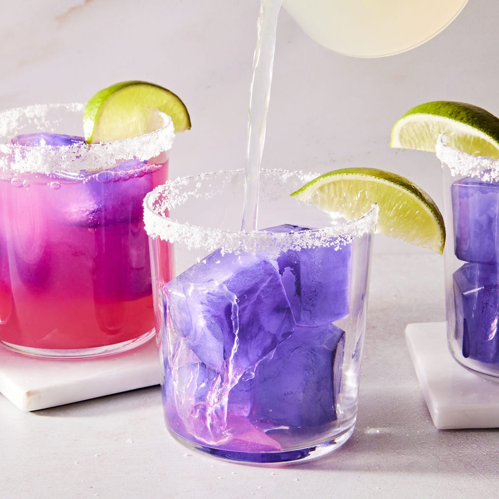 pink margarita with a purple ice cube with a salt rim and lime wedge