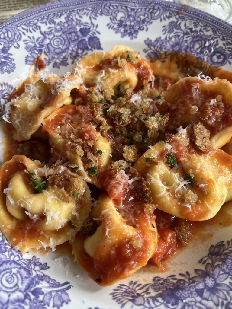 Four cheese Cappeletti in a tomato sauce. Topped with Parmigiano and crispy breadcrumbs seasoned with lemon zest and parsley.