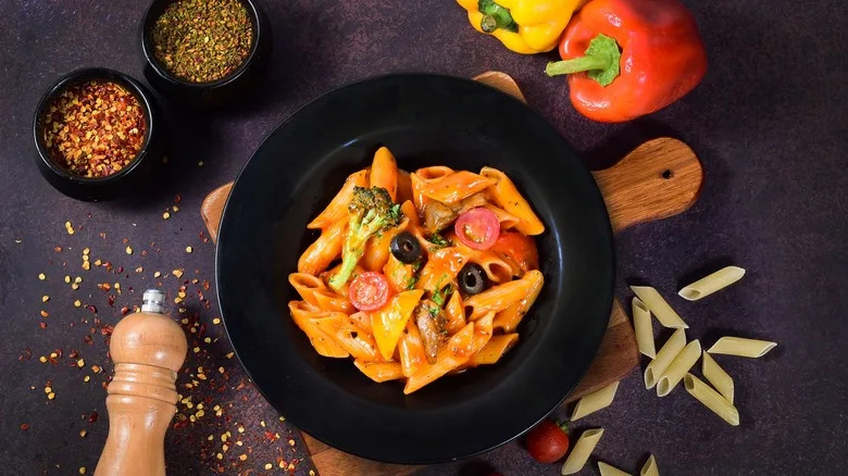 A bowl of arrabbiata sauce and pasta from above, surrounded by ingredients