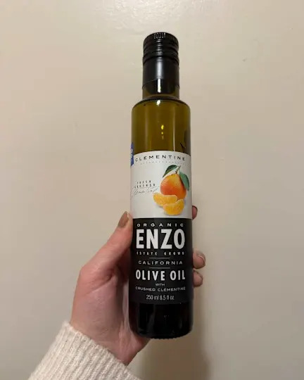 Someone holding up bottle of Enzo's Table clementine olive oil.