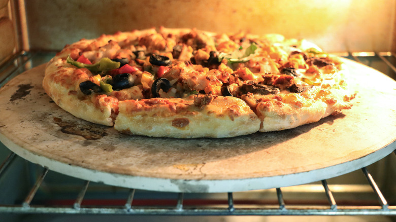 Pizza cooking on top of stone peel