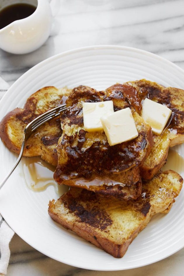 french toast on a plate topped with maple syrup and pats of butter