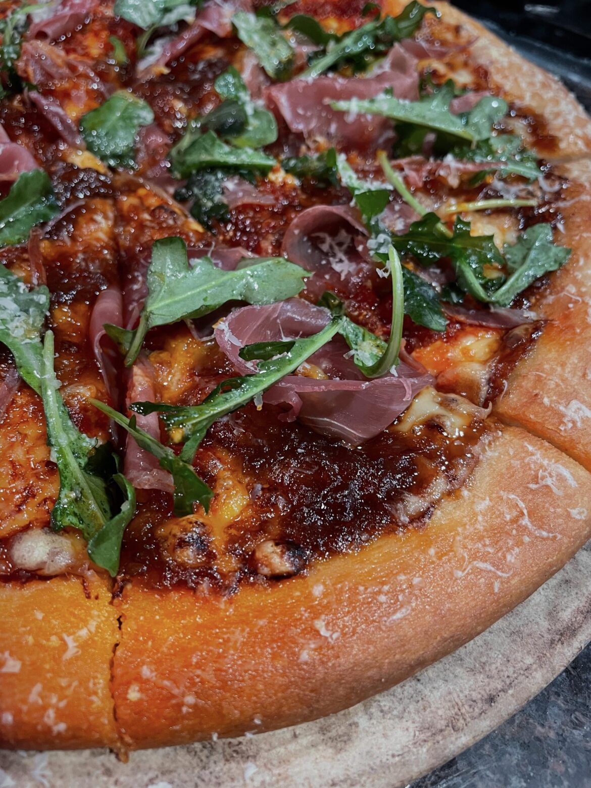 Made pizza with fig jam, fontina, gorgonzola, jammy caramelized onion, calabrian chili paste, prosciutto, and arugula.
