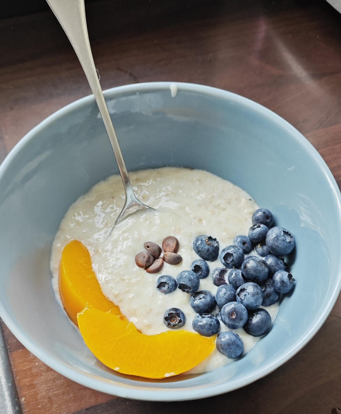 Porridge with greek yoghurt, blueberries, peach and dark chocolate chips
