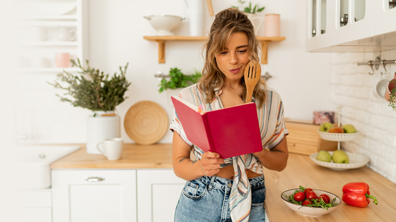 Woman in kitchen reading book