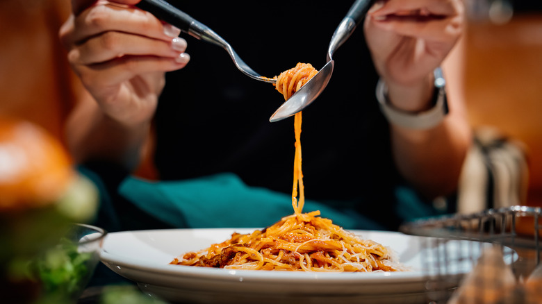 person eating spaghetti dish at a restaurant