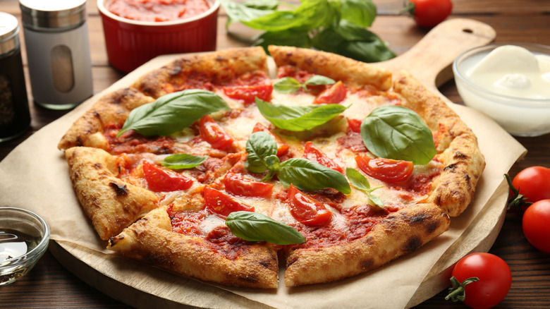 Homemade pizza on wooden table with ingredients