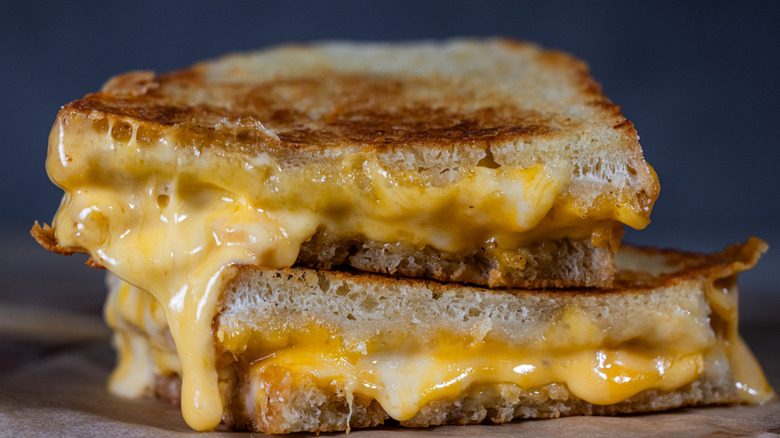A grilled cheese sandwich cut in half with melted cheese seeping out