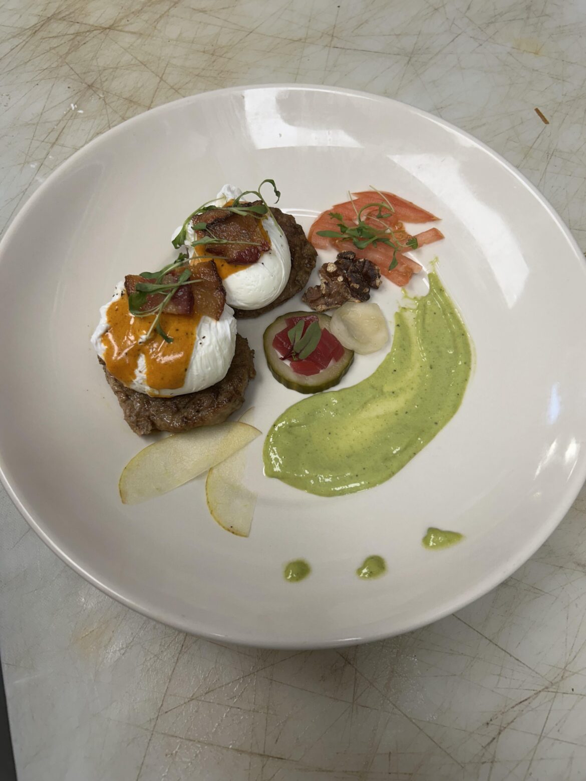 Turkey egg benny with bacon and holandaise pickle with pickle onions, pesto aioli, walnut, tomato, and 2 slices of apple and micro greens
