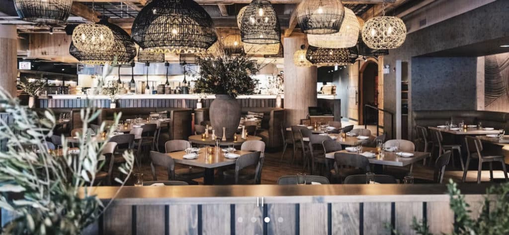 Lyrà in chicago with light fixtures, round tables, and plants around the restaurant