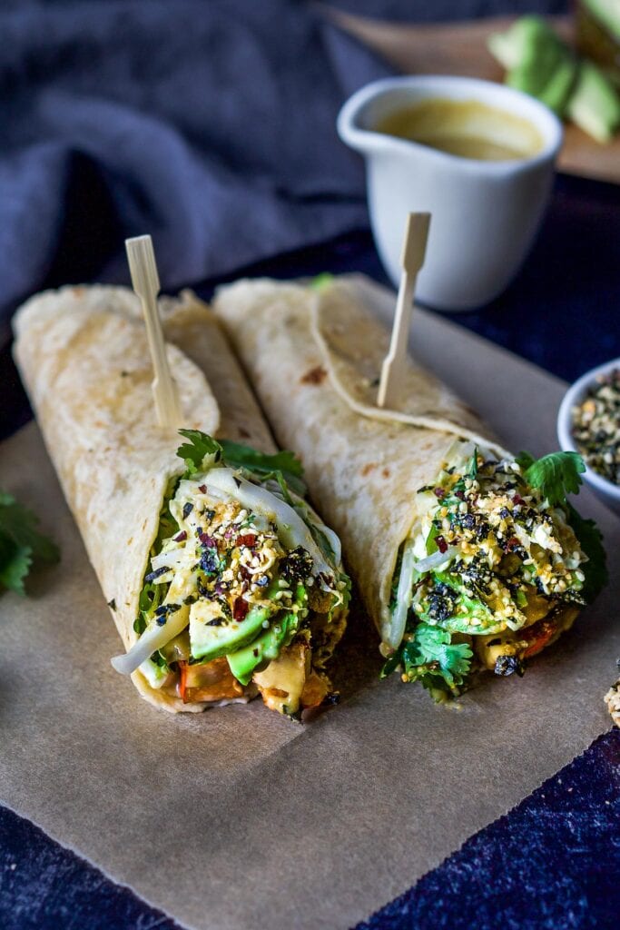 miso tofu wraps with winter squash, avocado, slaw, herbs, and furikake, wrapped in tortillas and held together with toothpicks.