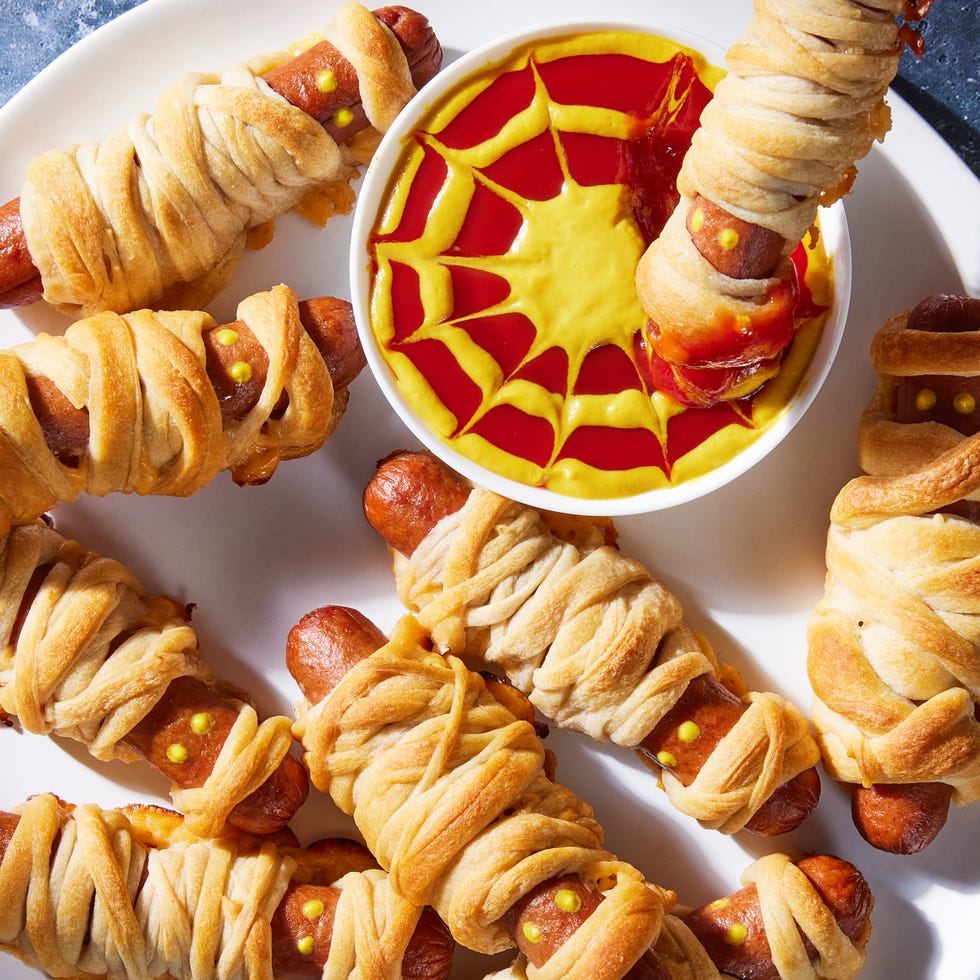 hot dogs with mustard eyes wrapped in crescent dough with cheese and served a mustard and ketchup dip