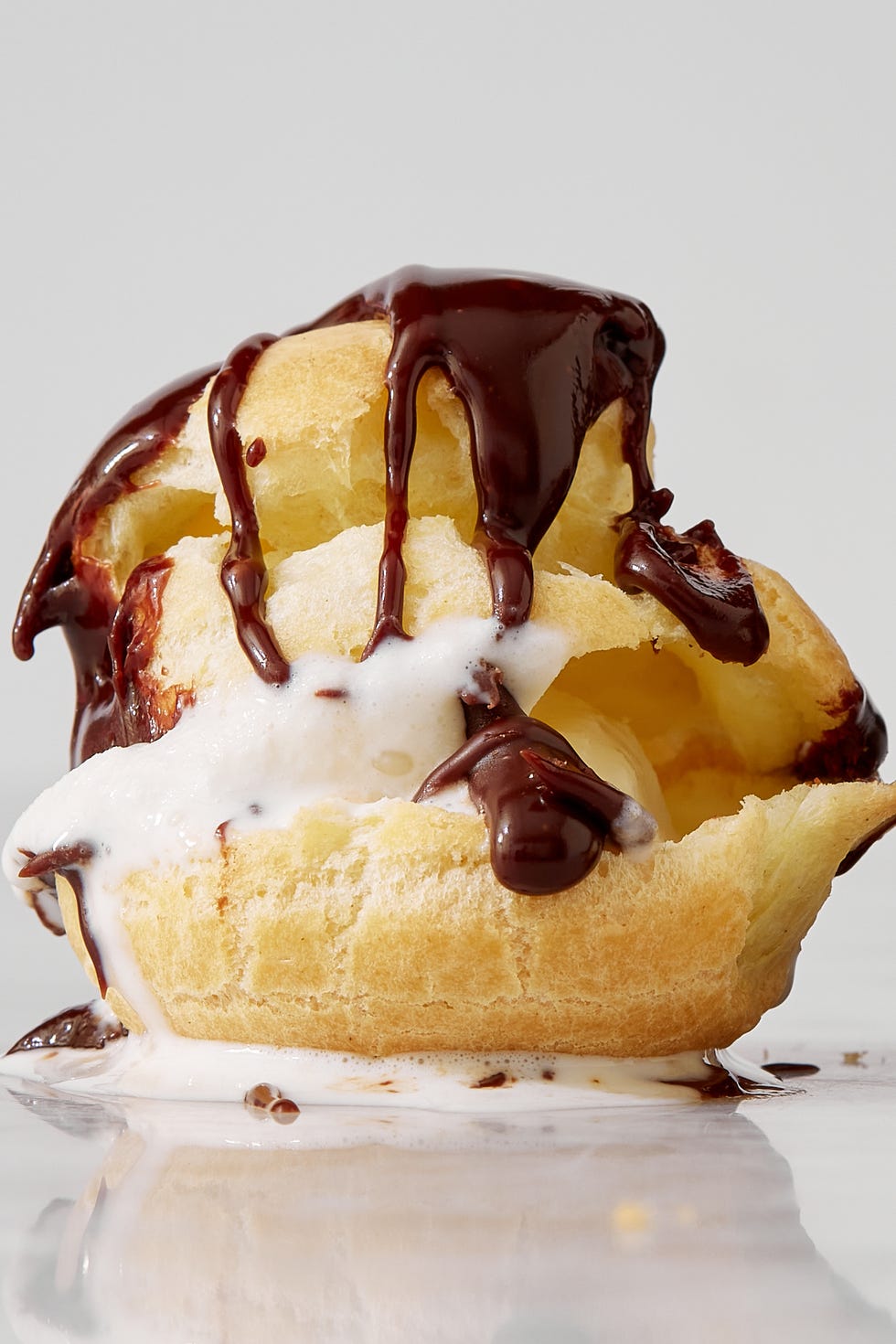 closeup of an ice cream filled profiterole topped with chocolate sauce