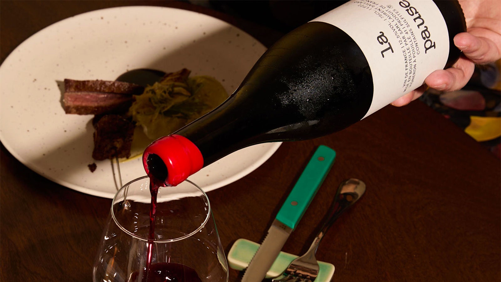  Bottle of red wine poured in front of dishes at Claudine in Providence, Rhode Island