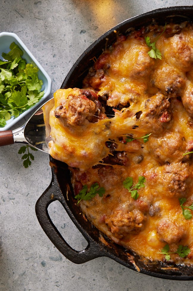 chili and meatballs in a cast iron skillet, topped with melty cheese
