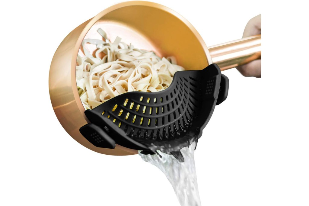 A pot with noodles being poured into a strainer