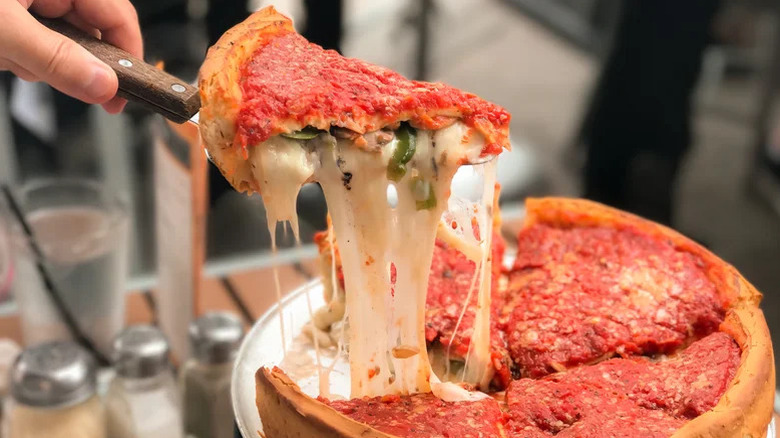hand holding spatula with slice of stuffed deep dish pizza