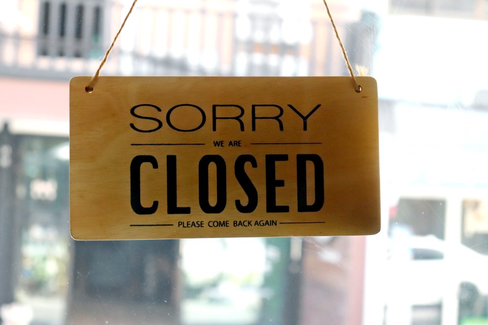 Wooden sign that says "Sorry we are closed. Please come back again." hanging on a door.