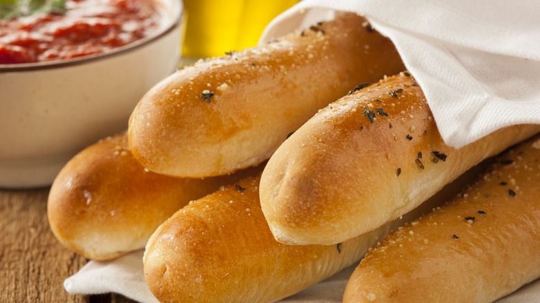 fresh breadsticks with a bowl of marinara in the background
