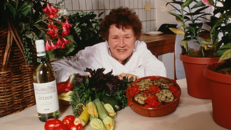 Julia Child posing in front of a dish and fresh produce