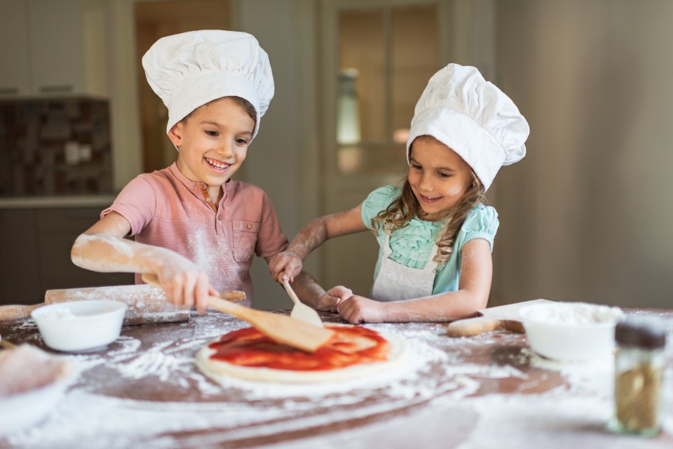 Two toddlers making pizza.